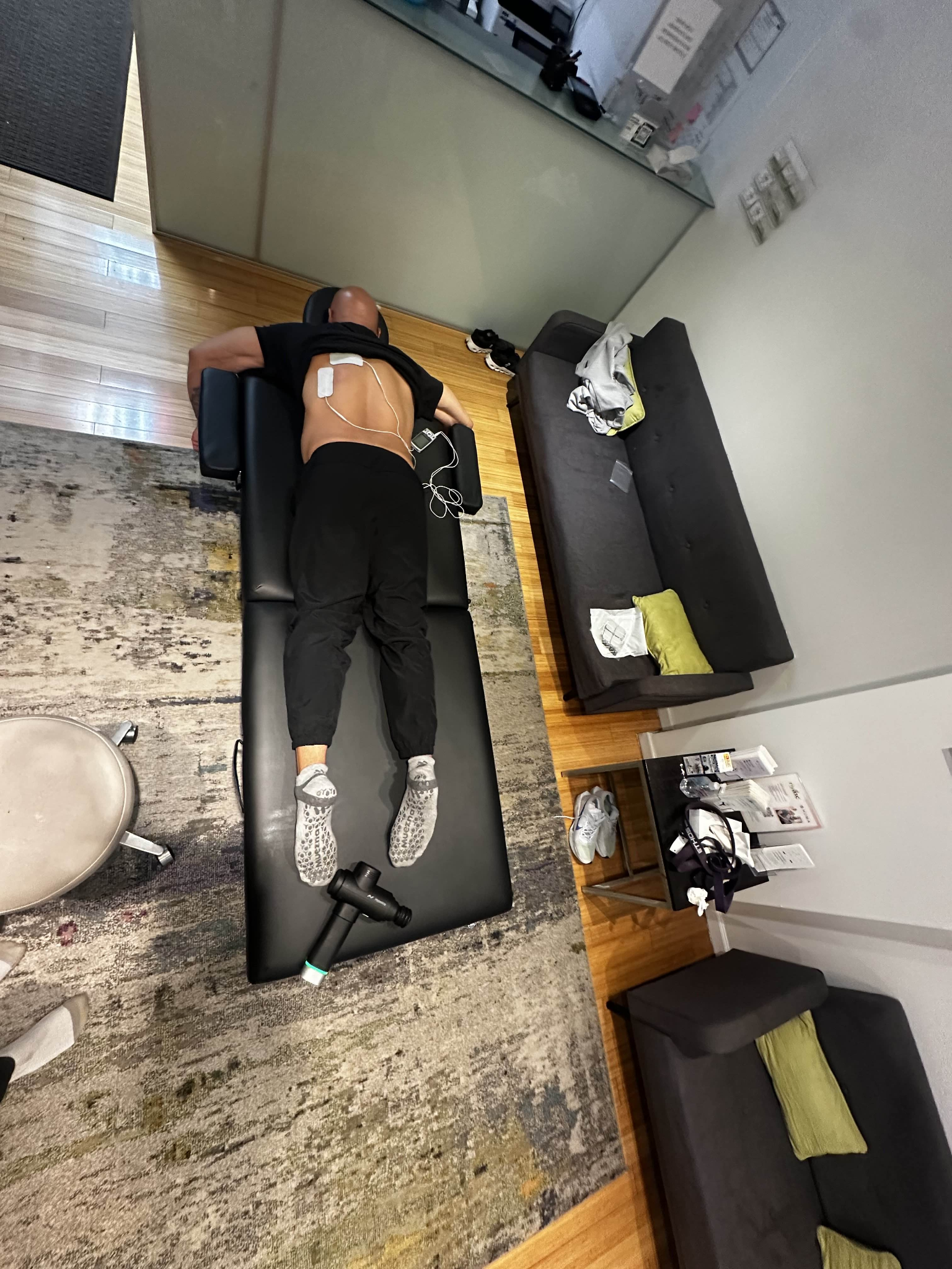 Client face down on black table with stim pads, closer view of back